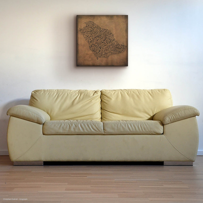 Beige sofa in a room with a textured wall art piece, a carved wood artwork of the Saudi Arabia map