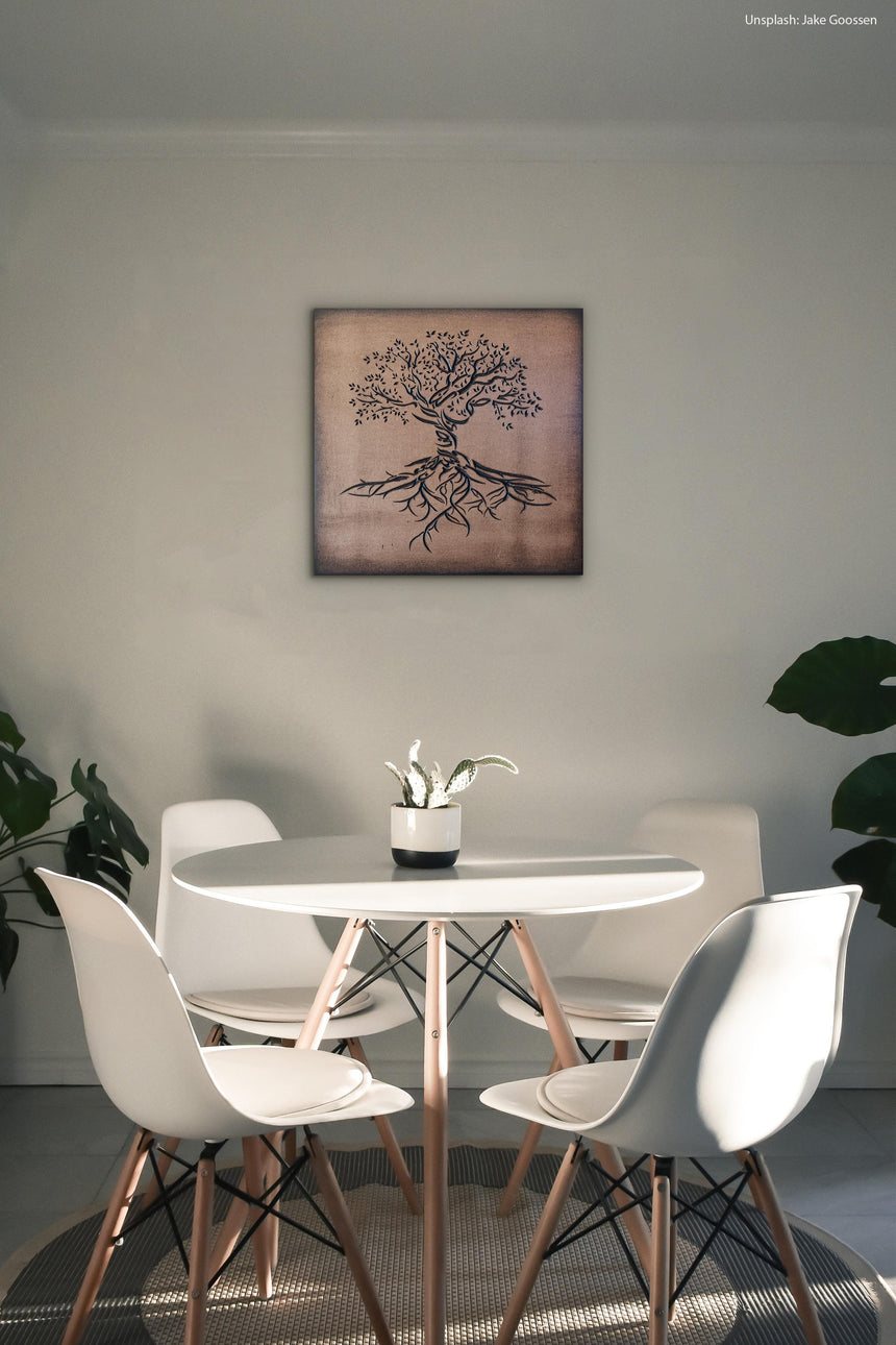 Wooden artwork of an olive tree with the Arabic phrase “The land is ours, and to it we return.” in a living room.