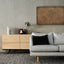 a living room with a gray couch and a wooden cabinet