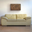 a white couch sitting in a living room under a painting